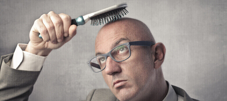 Άντρας ο οποίος χτενίζει το φαλακρό του κεφάλι με βούρτσα μαλλιών